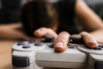 Uupunut pelaaja, peliohjain lattialla käsi ohjaimen päällä
